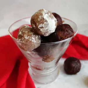 Stemless martini glass filled with bourbon balls coated in powdered sugar and cocoa powder.