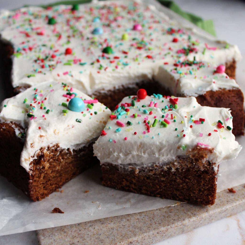 Gingerbread cookie bars with fluffy white buttercream frosting and sprinkles on top.