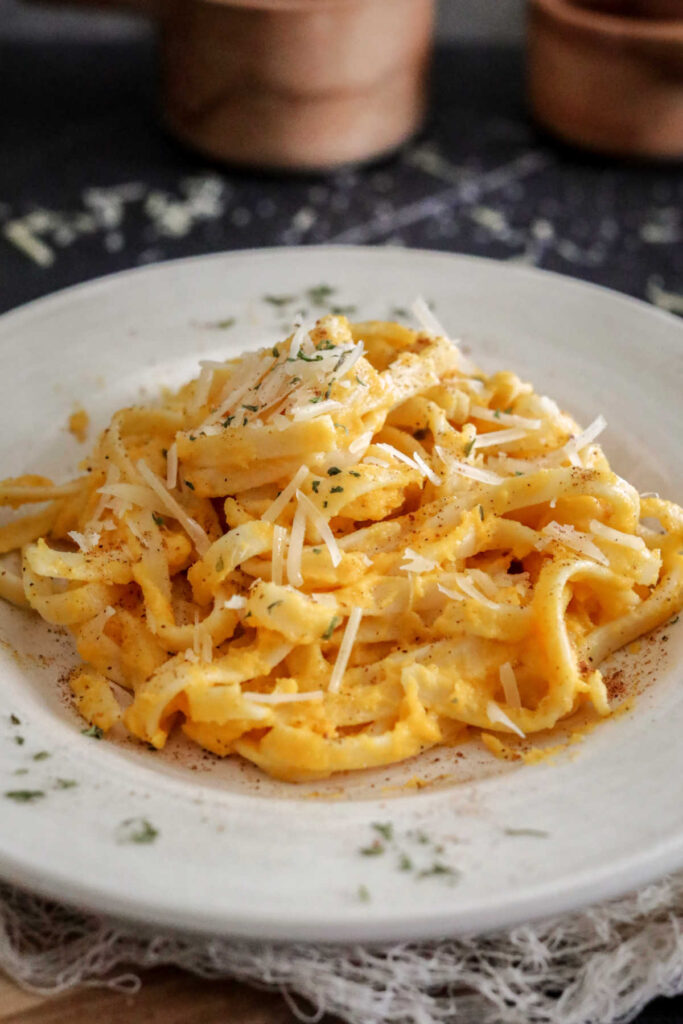 Plate of fettucine pasta coated in butternut squash alfredo sauce with a sprinkling of parsley. 