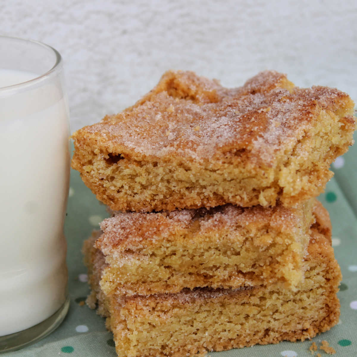 Cinnamon sugar topped snickerdoodle cookie bars next to cup of milk.
