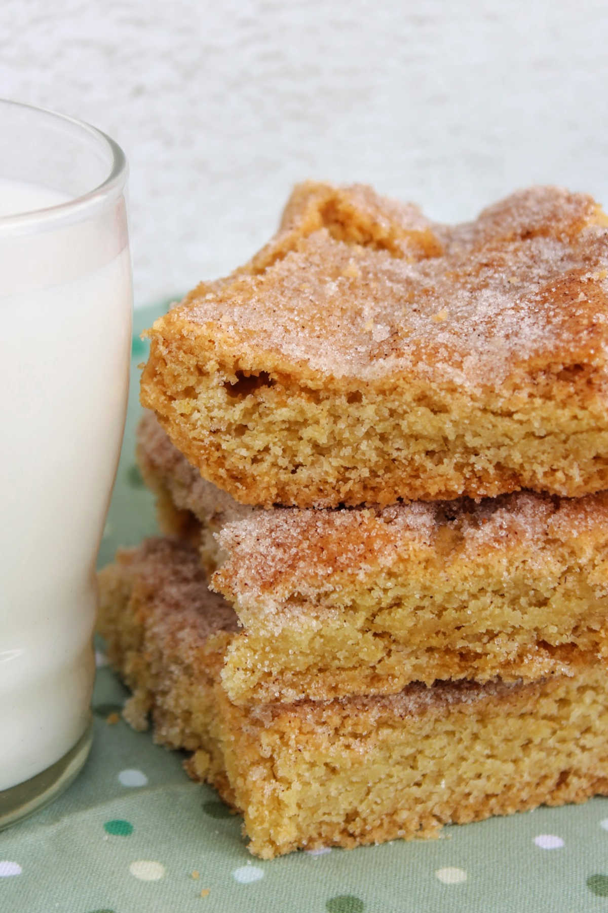 Stacked snickerdoodle bars next to glass of milk.