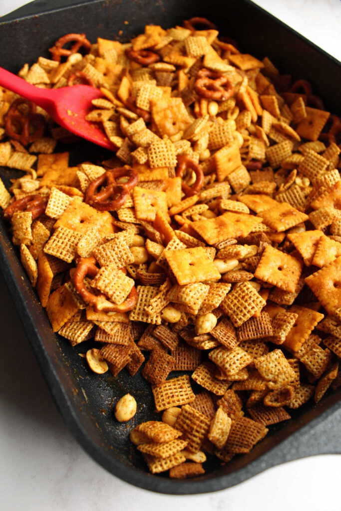 Stirring baked taco chex mix in large roasting pan.