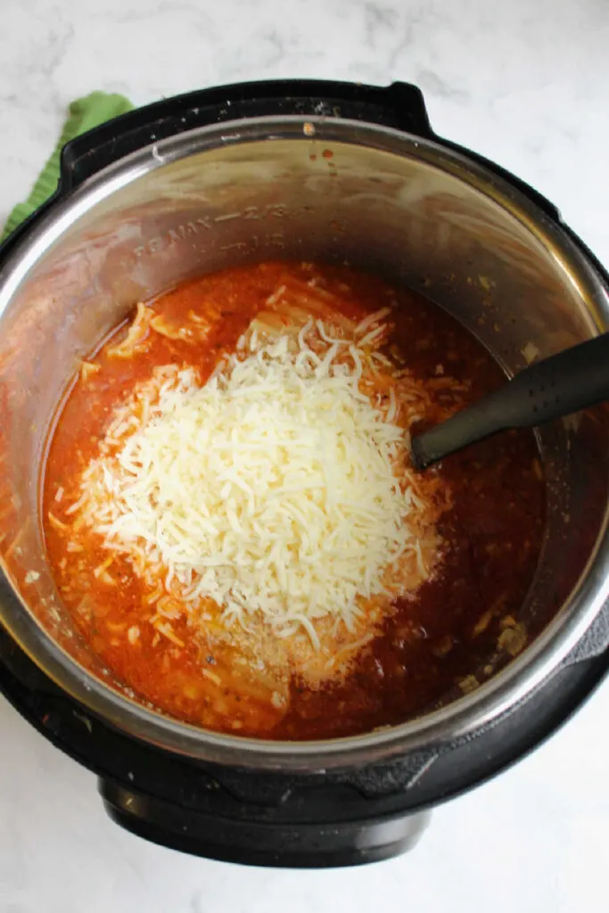 Stirring cheeses and marinara sauce into the soup.