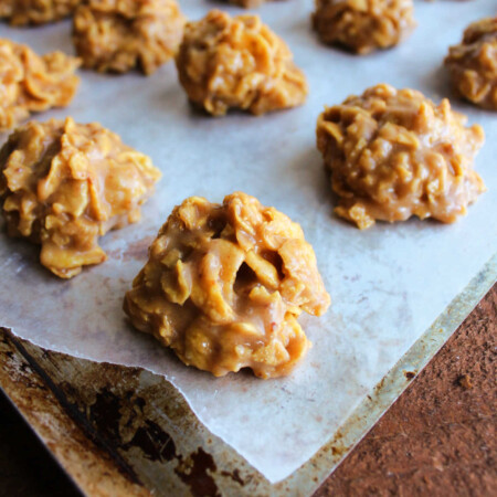 mounds of peanut butter honey cornflake cookies on wax paper lined pan, ready to eat.