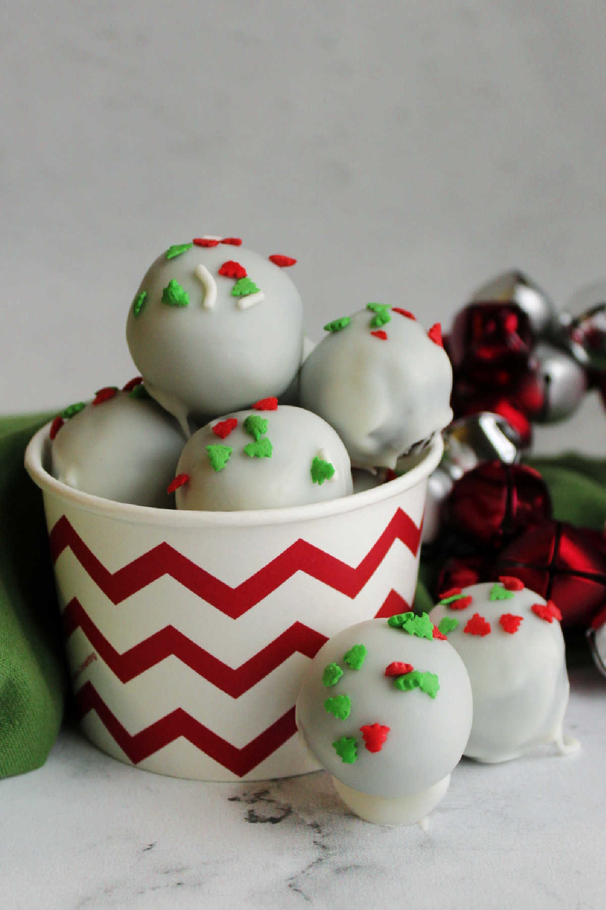 Cup of white chocolate coated oreo balls topped with festive Christmas sprinkles.
