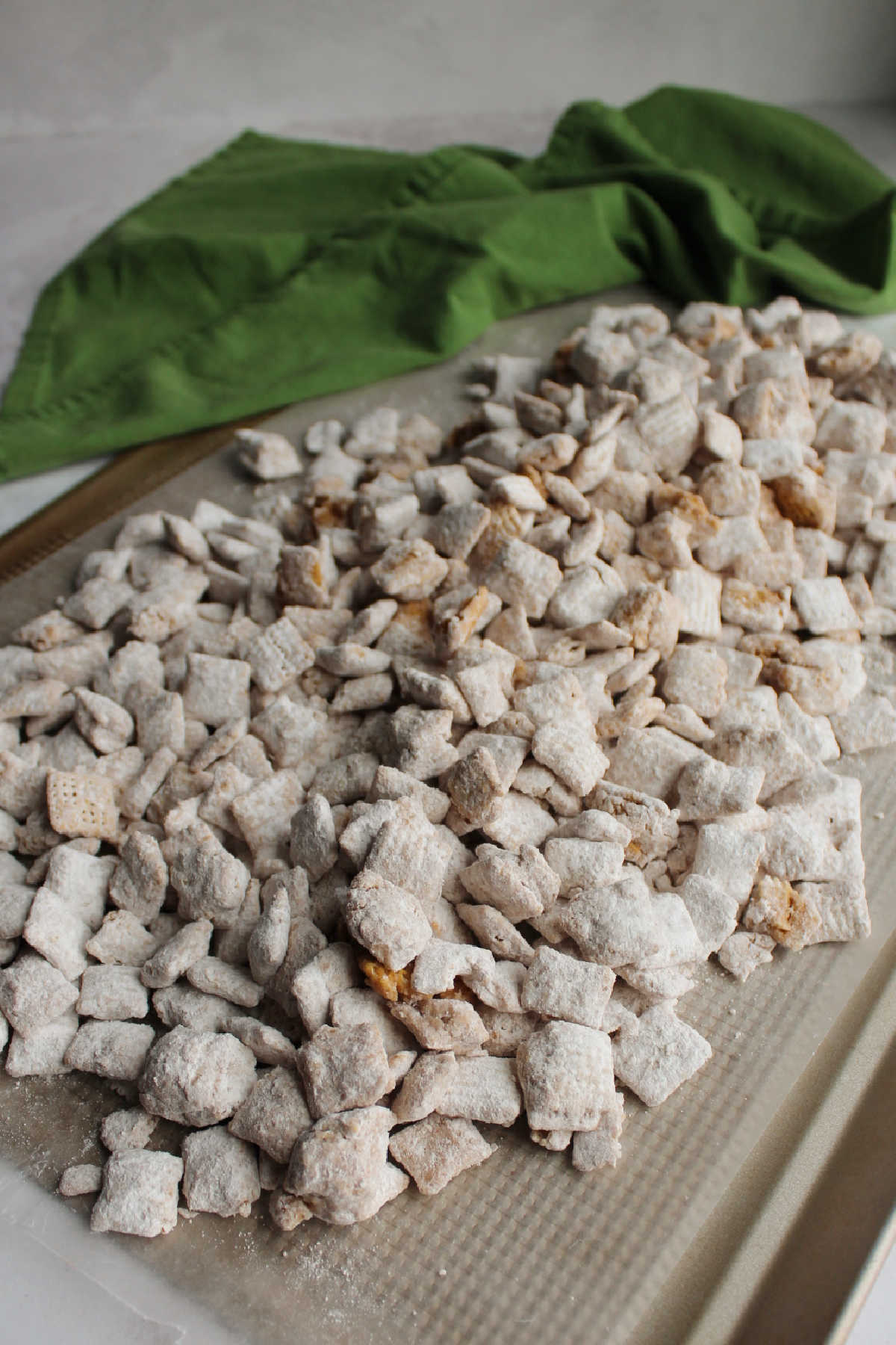 Powdered sugar coated maple cinnamon muddy buddies spread out on wax paper to set.