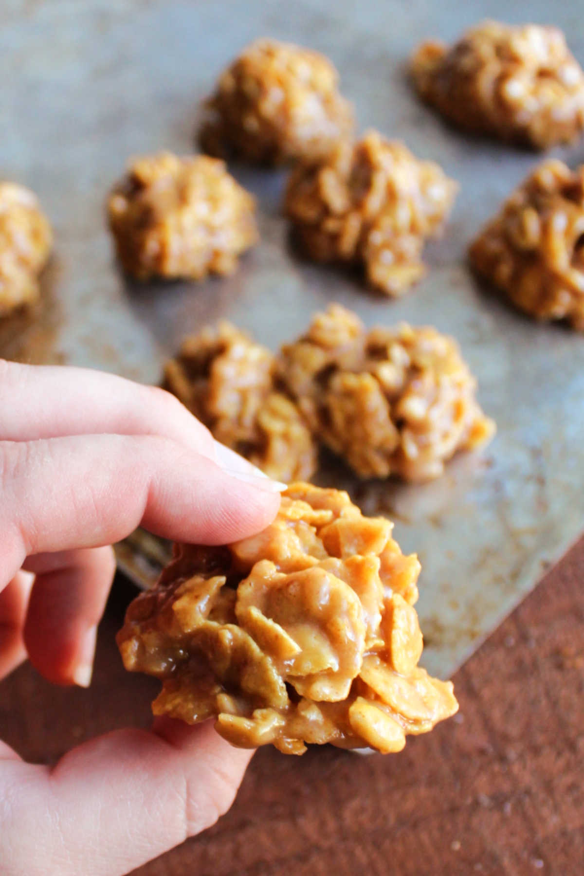 Hand holding peanut butter and honey cornflake cookie.