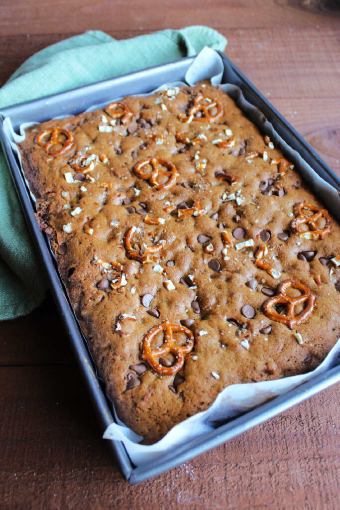 Pan of freshly baked kitchen sink bars topped with pretzels and chocolate chips.