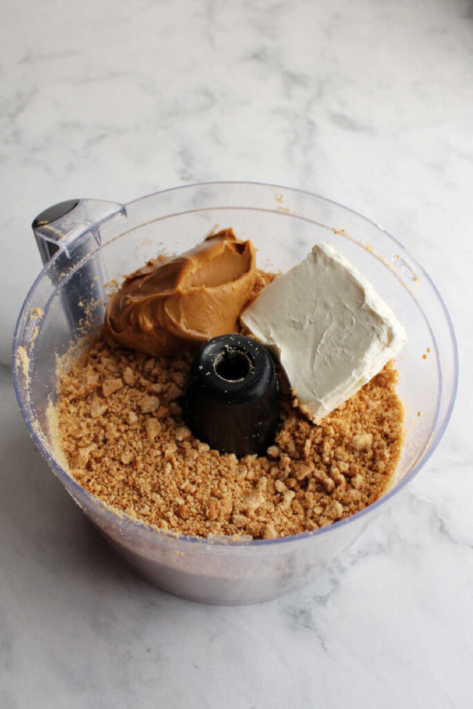 Cookie crumbs, cream cheese and peanut butter in food processor.