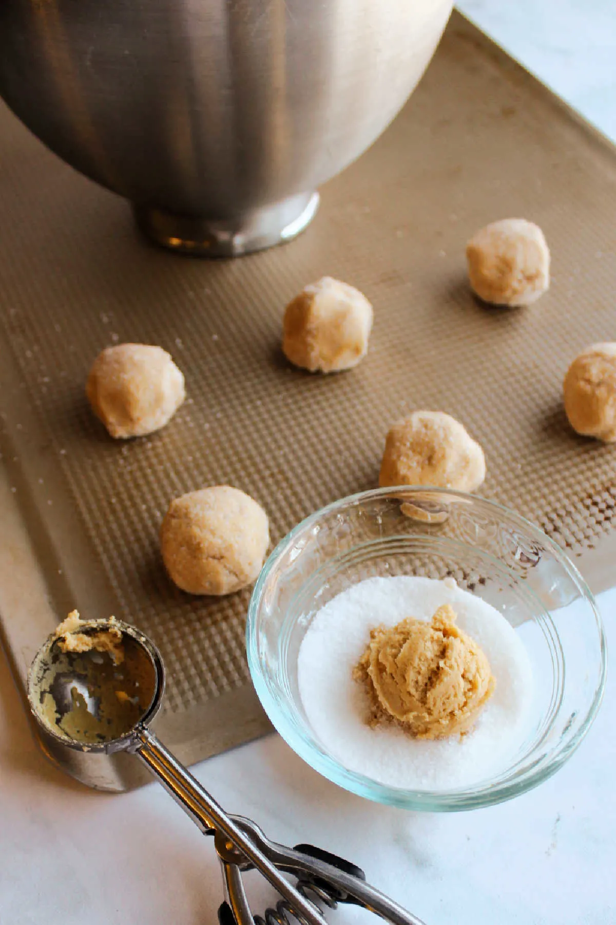 Rolling balls of peanut butter cookie dough and placing them on cookie sheet. 
