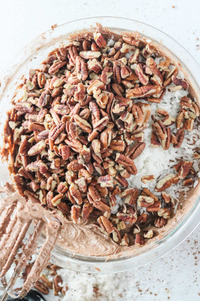 Mixing chopped pecans and coconut into chocolate cake batter.