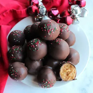 Plate of chocolate dipped nutter butter truffles with the peanut butter center of one showing.