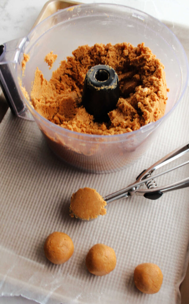 Using small cookie scoop to portion out peanut butter cookie ball mixture.