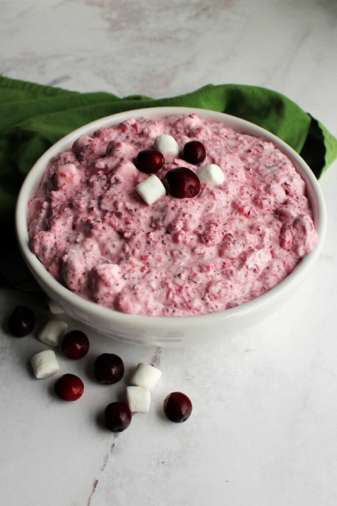 Bowl of cranberry fluff salad with fresh cranberries and marshmallows.