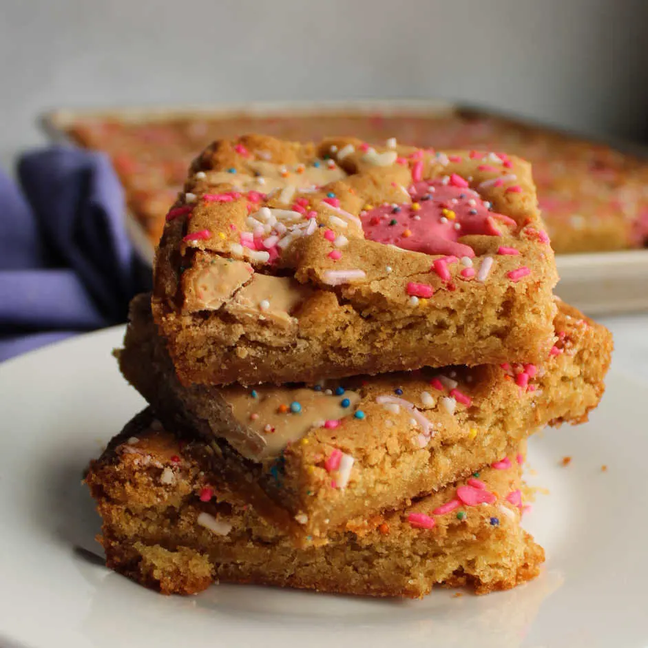 Stack of blondies with frosted circus animal cookies and sprinkles baked in.