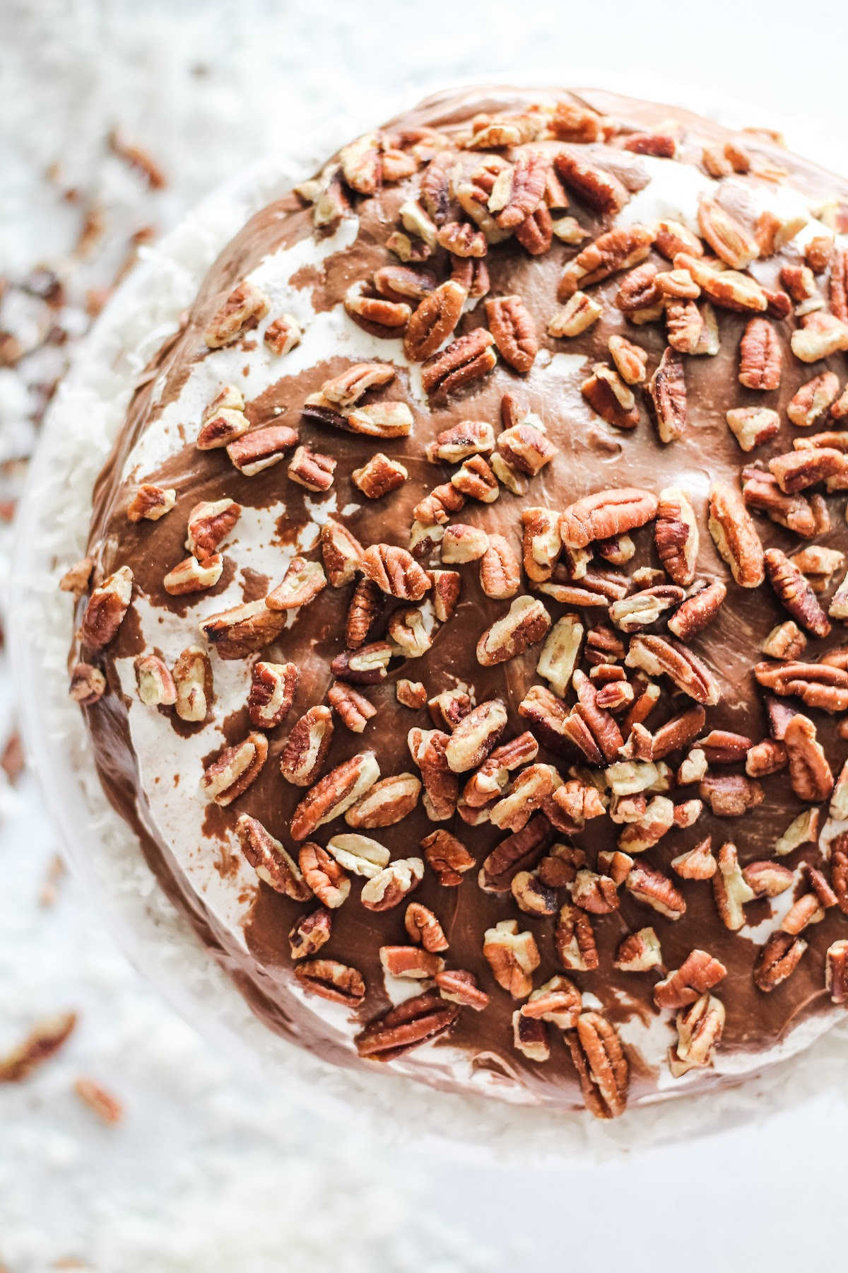 Looking down on whole mudslide cake with marshmallow fluff showing through chocolate icing and pecans.