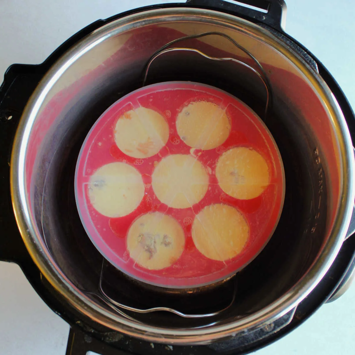 Silicone mold filled with egg mixture with lid on in instant pot ready to cook.