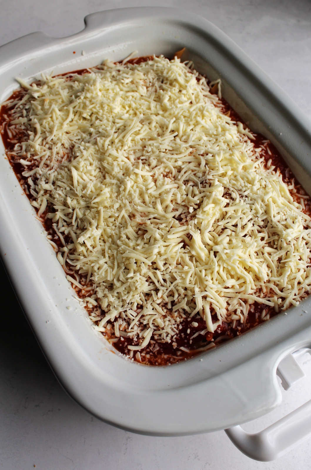 Shredded mozzarella over pasta in slow cooker.