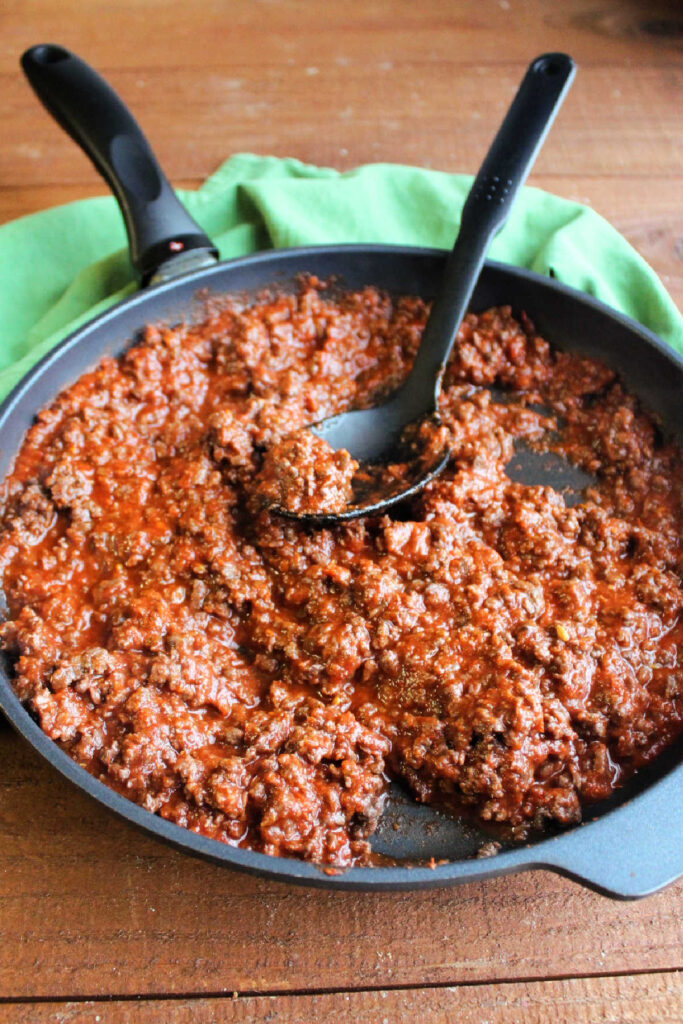 Skillet filled with browned ground meat and pizza sauce.