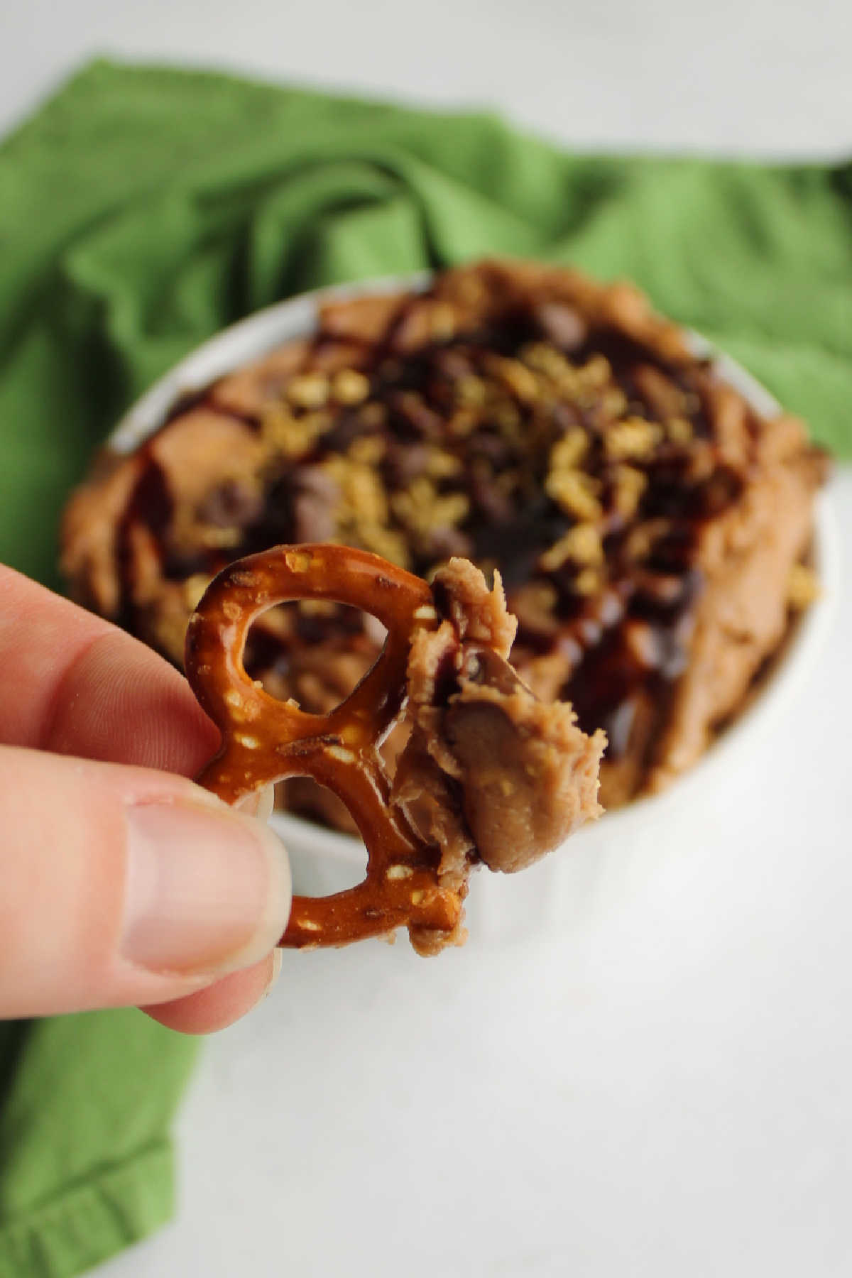 Hand holding pretzel dipped in puppy chow dip.