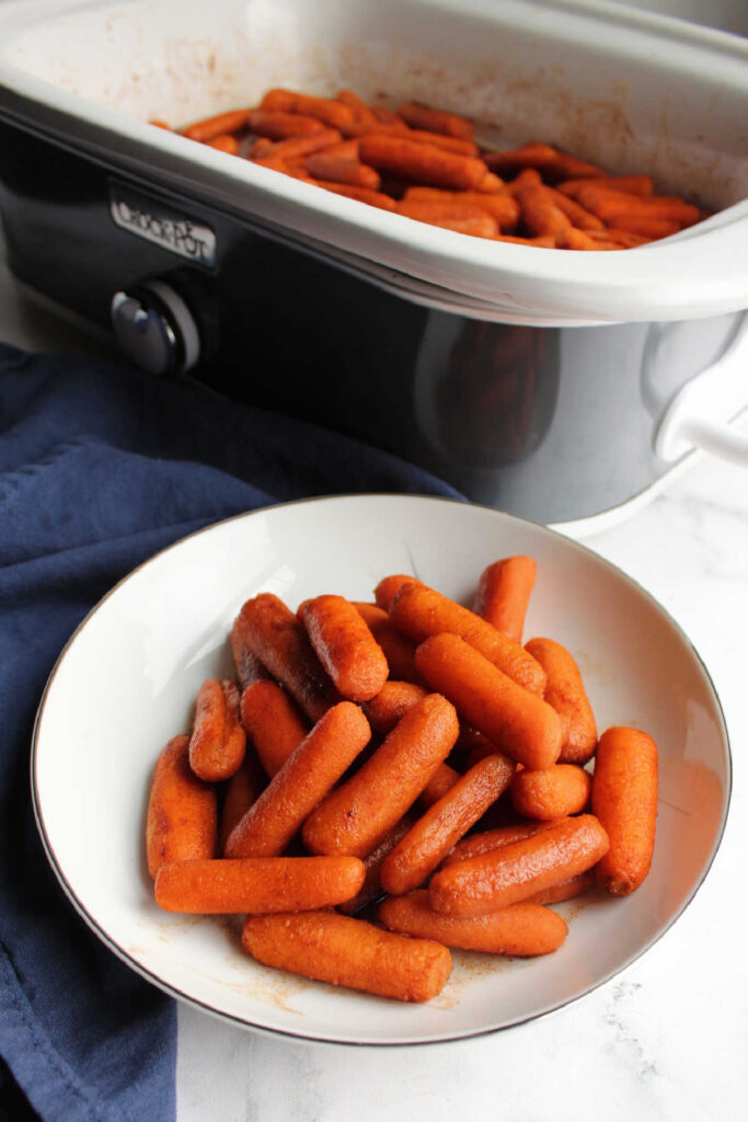 Crockpot filled with honey glazed baby carrots with cinnamon and ginger.