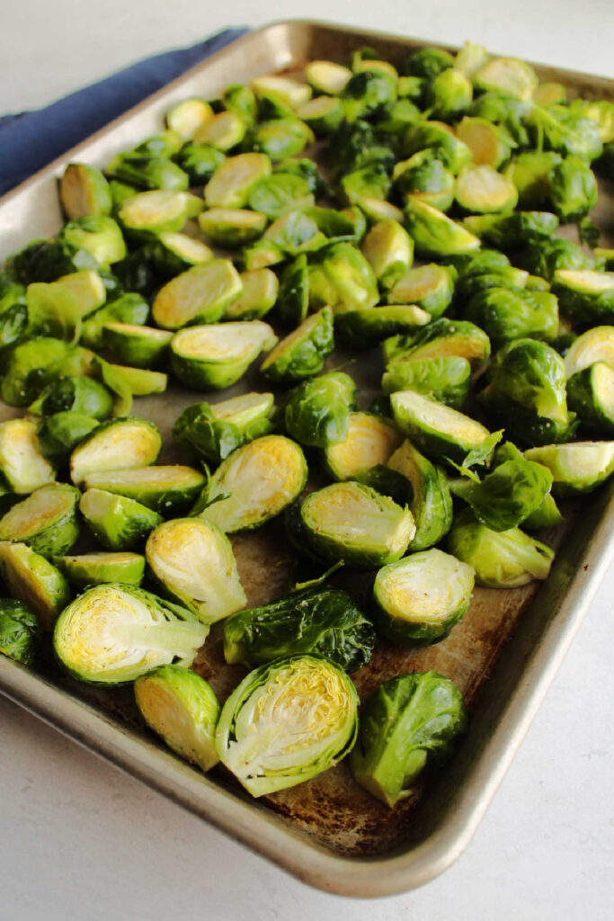 Lemon and garlic salt coated brussels sprouts on pan ready to roast.