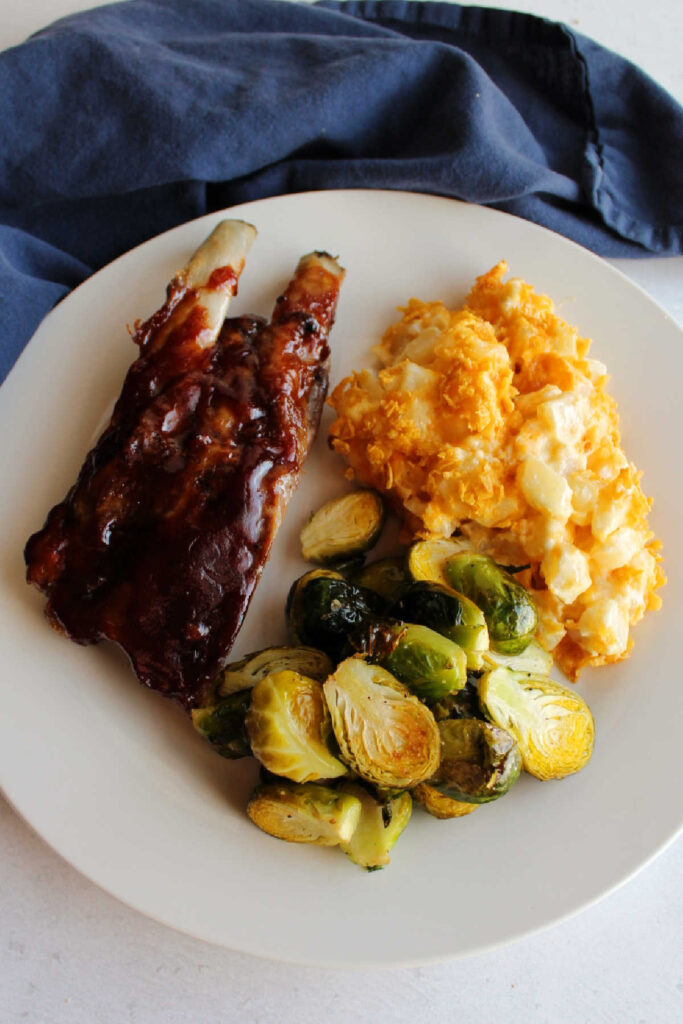 Ribs, cheesy ranch potato casserole and roasted brussels sprouts on plate. 