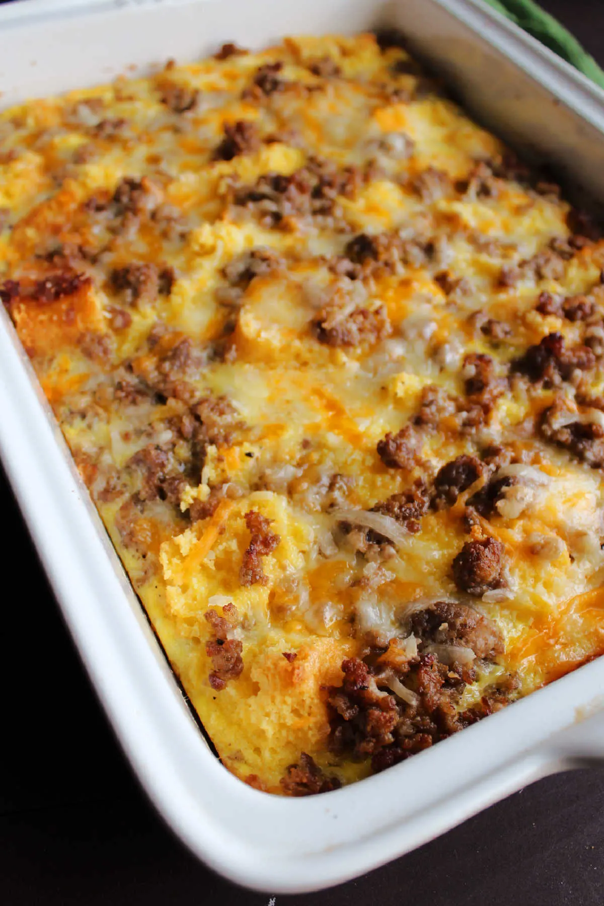 Freshly baked egg casserole with chunks of sausage and melted cheddar cheese on top.