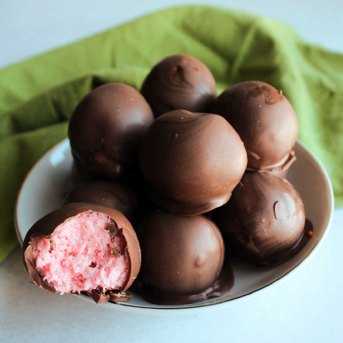Bowlful of truffles, one with the pink strawberry buttercream center showing.