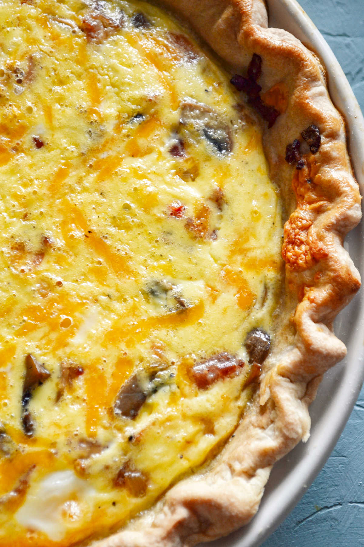 Looking down on freshly baked bacon quiche with peppers and mushrooms.