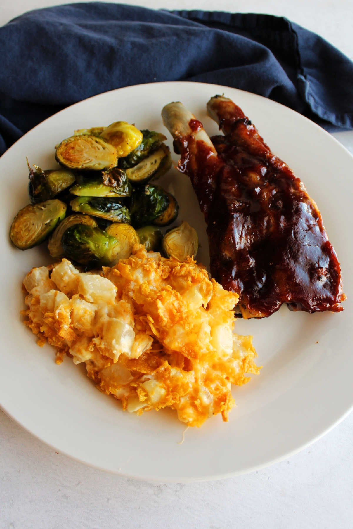 Dinner plate filled with cheddar ranch potato casserole, brussels sprouts and bbq ribs ready to eat. 