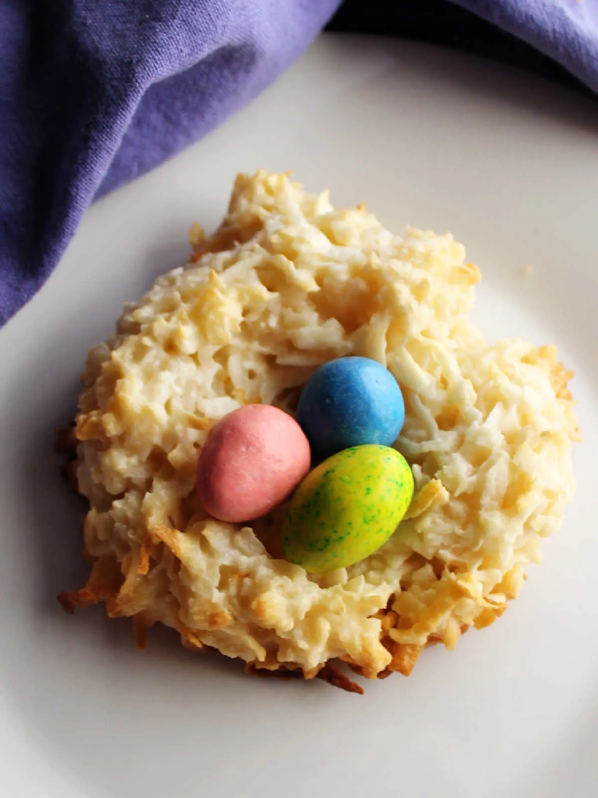 Close nest shaped coconut macaroon with pastel candy eggs inside. 