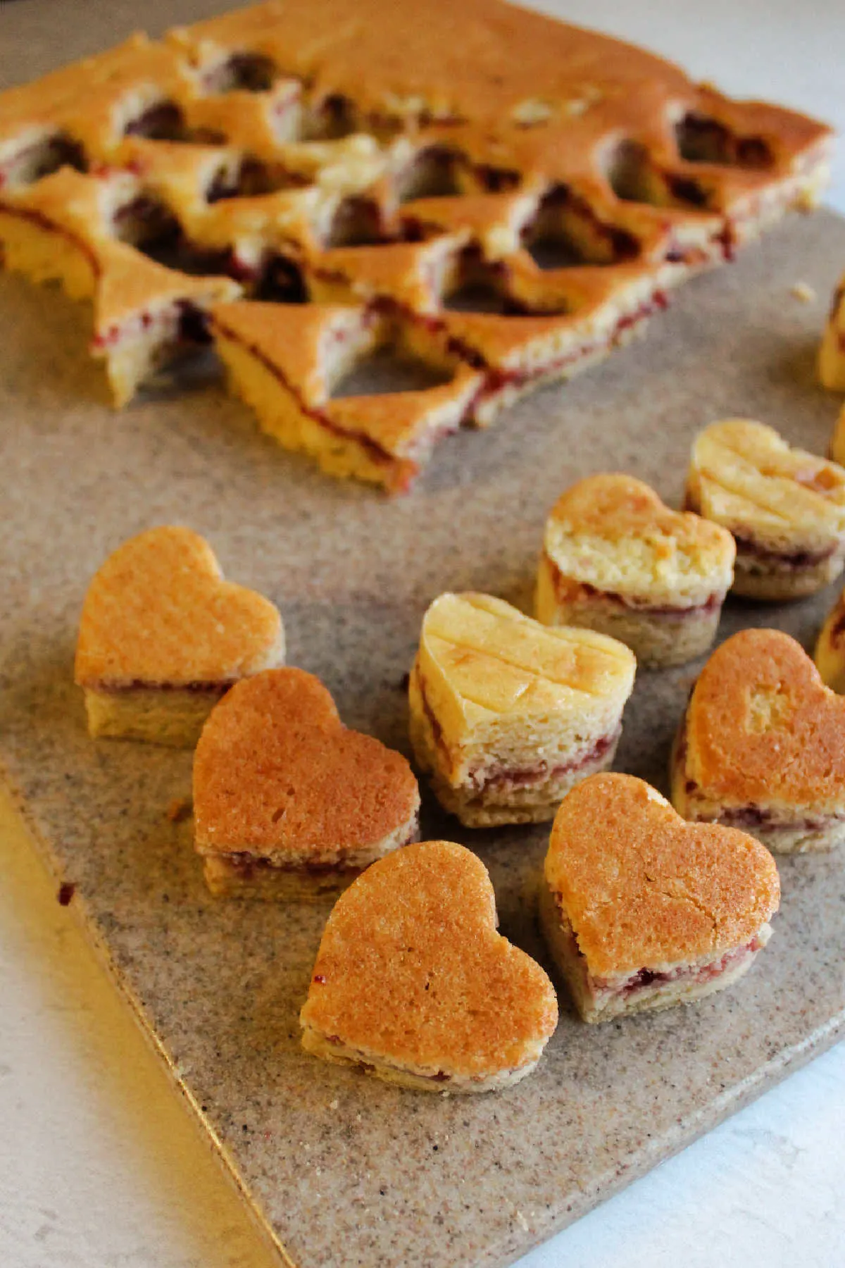 Cutting heart shapes out of raspberry filled petit four cake.
