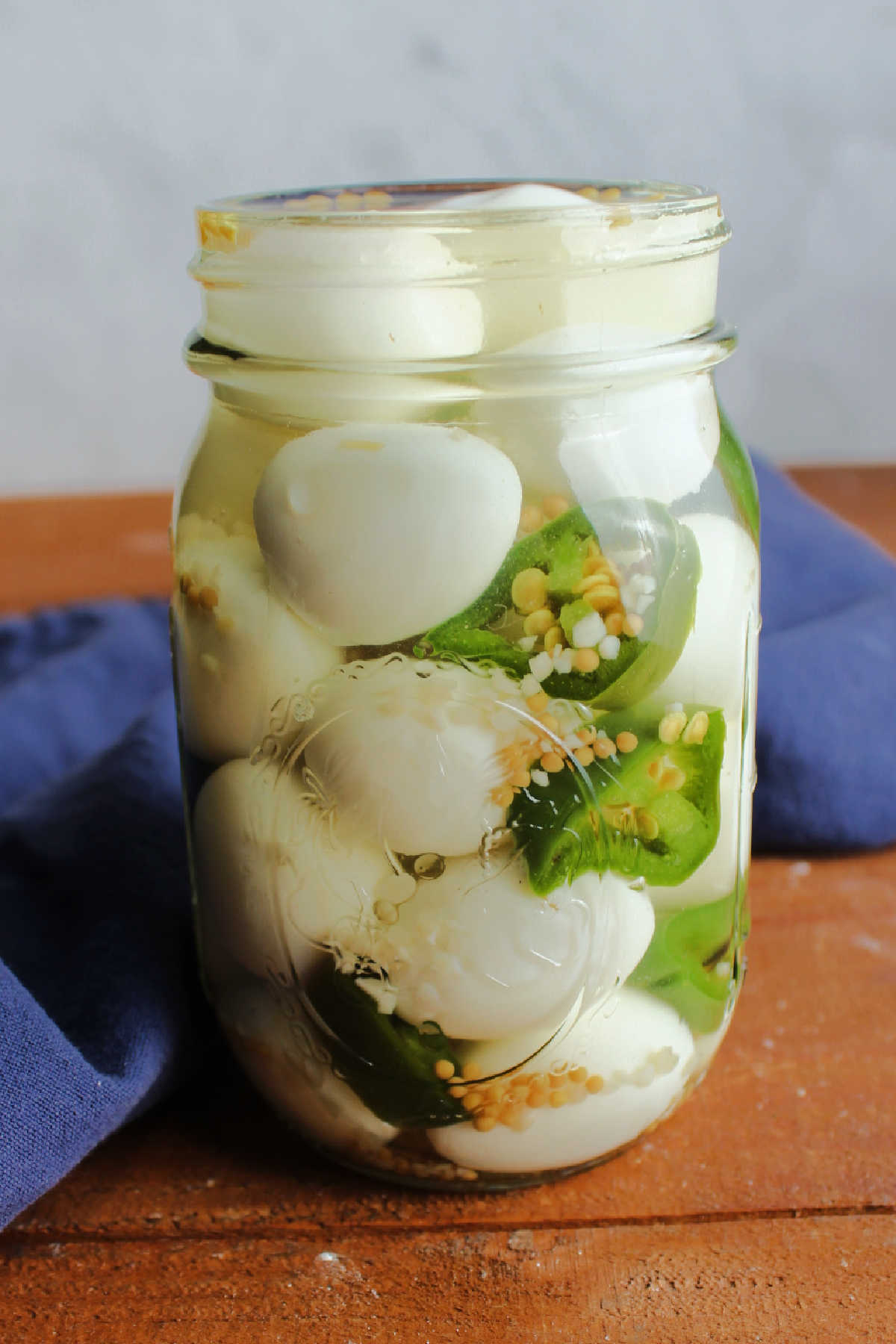 Jar of pickled quail eggs with sliced jalapenos ready to eat.