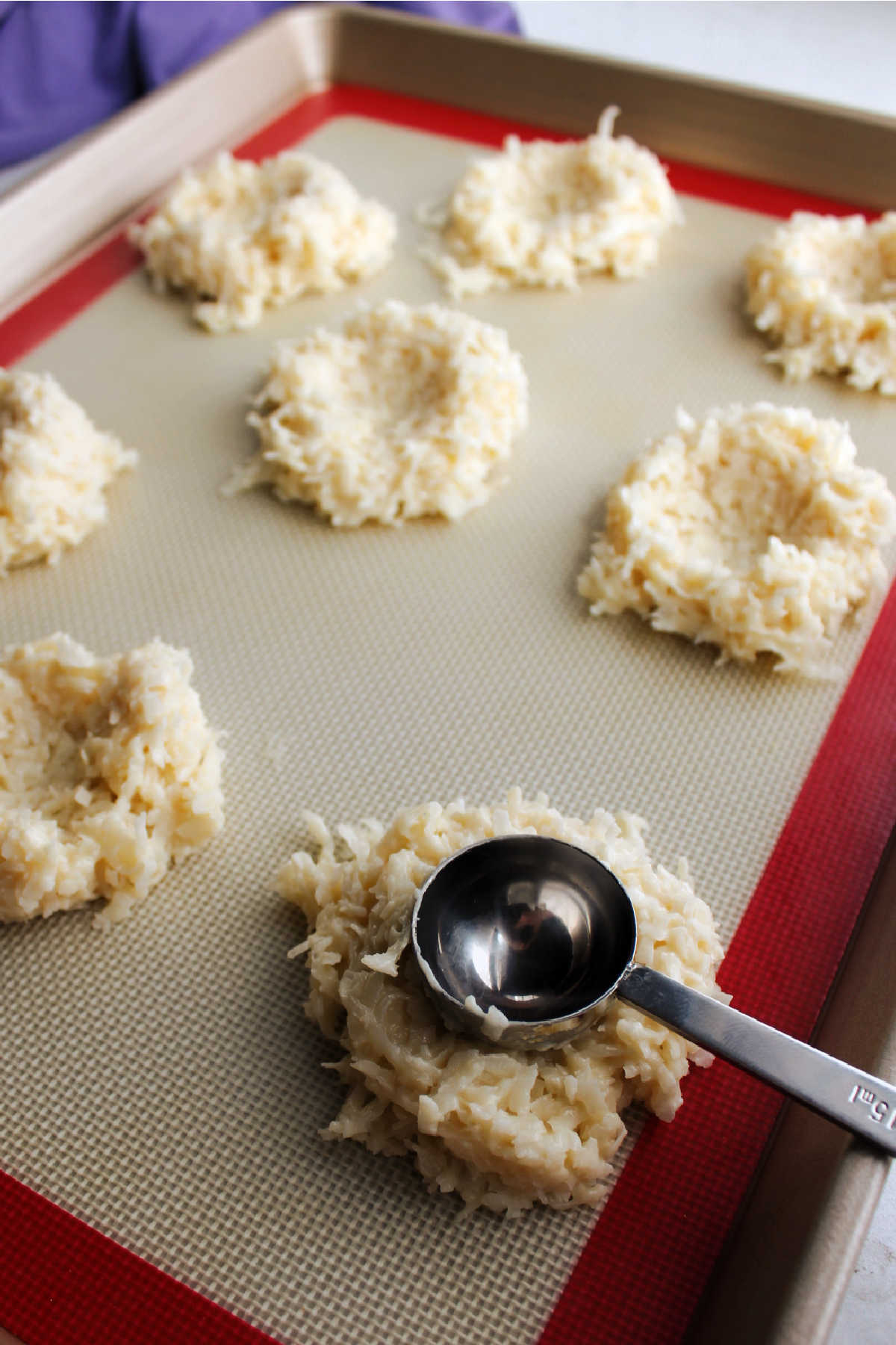 Pressing Tablespoon into the middle of a mound of coconut macaroon dough to make it a nest shape before it bakes.