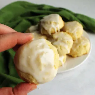 hand holding lemon cookie with white glaze on top.