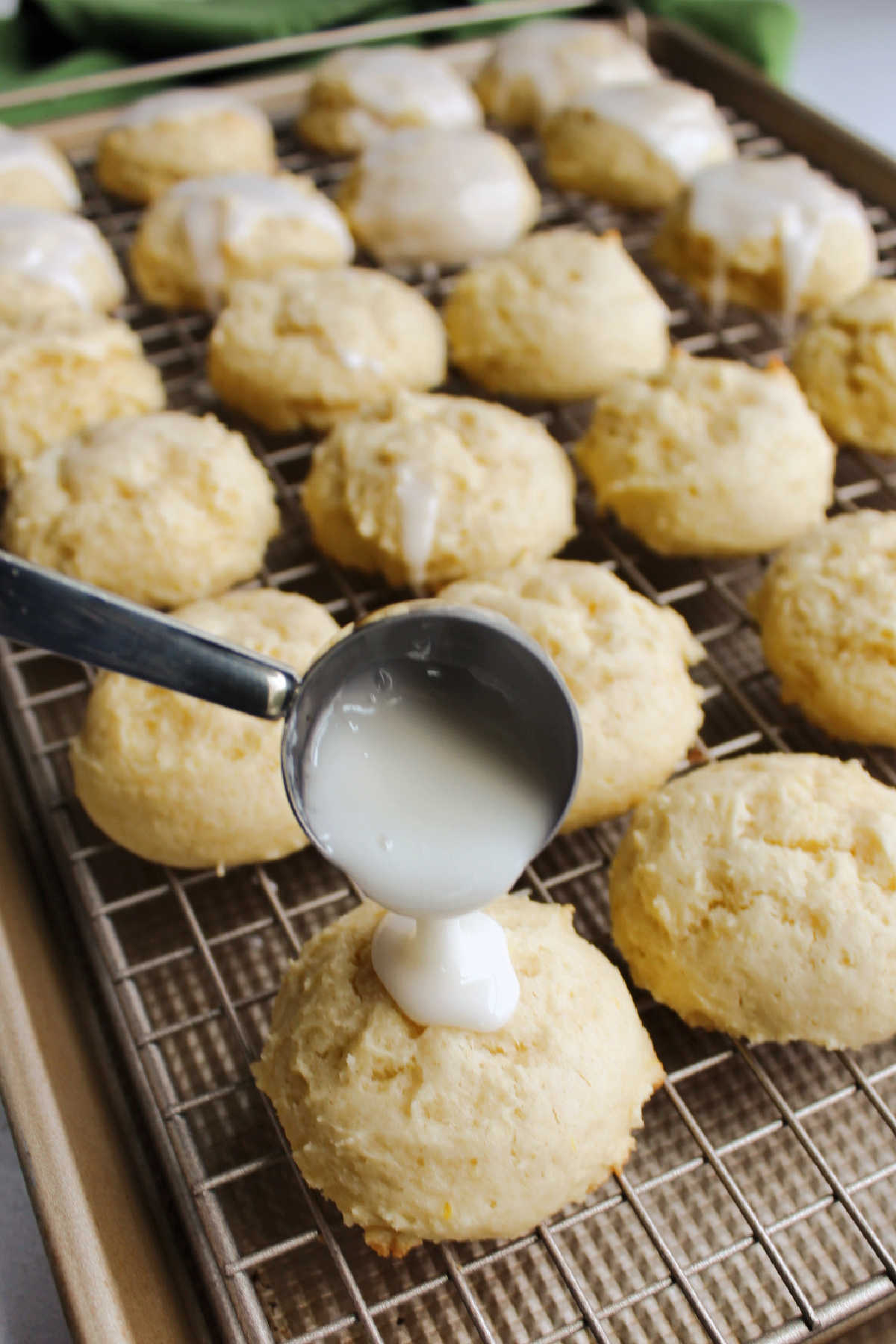 scooping powdered sugar glaze over cooled lemon cookie.