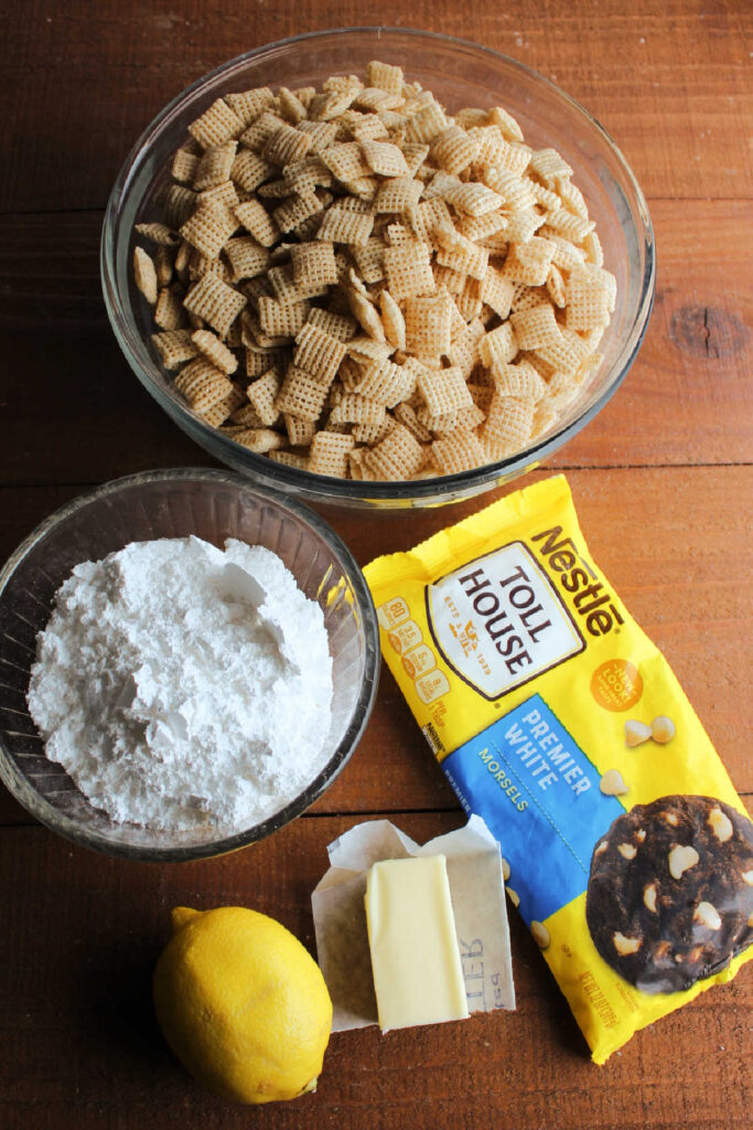Cereal, powdered sugar, butter, lemon, and white baking chips ready to be made into lemon muddy buddies.