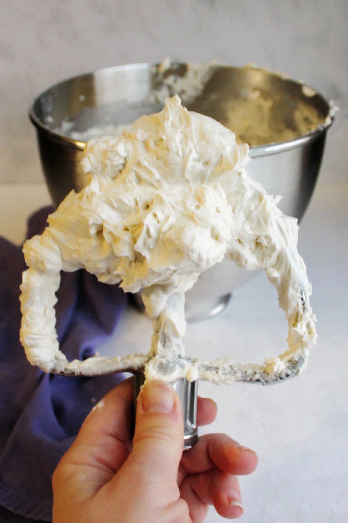 Hand holding mixer paddle filled with silky smooth faux swiss meringue buttercream. 