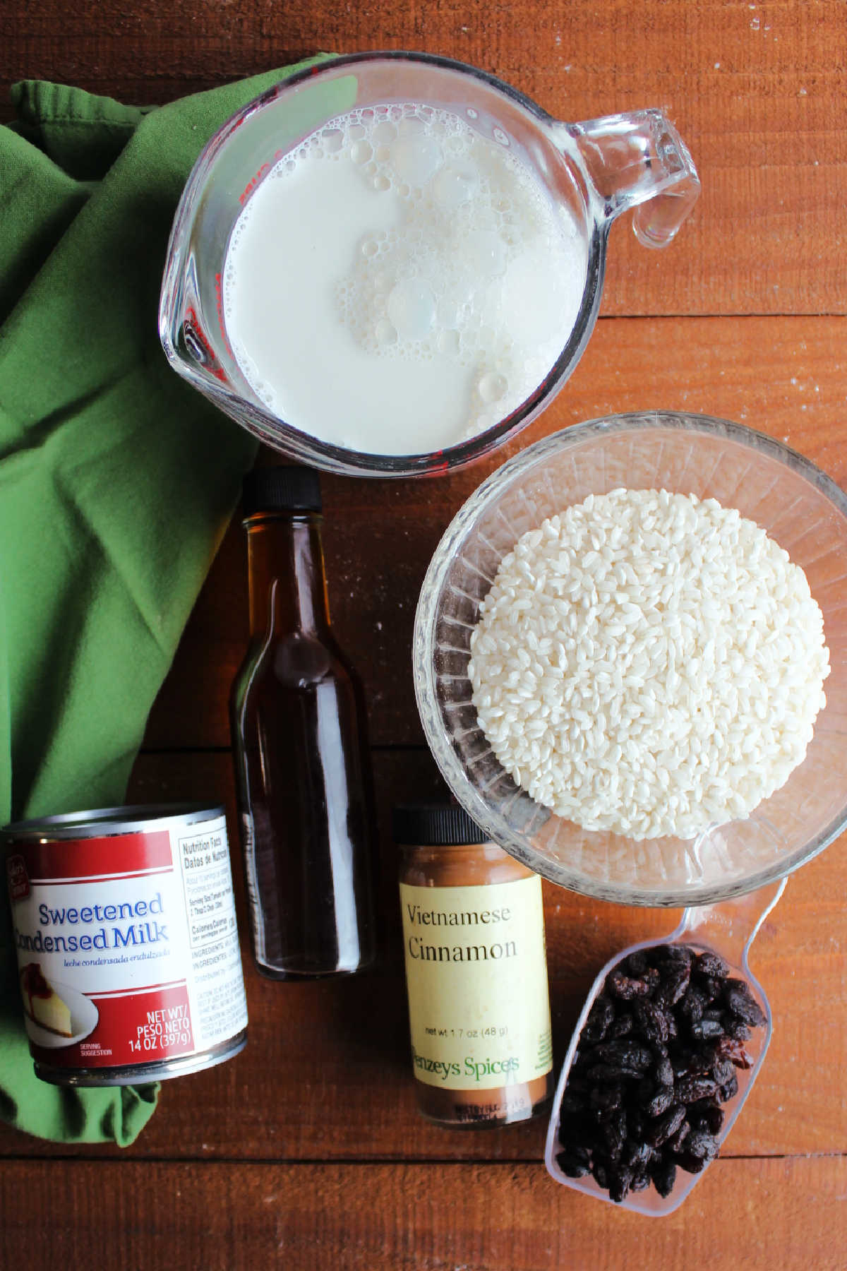Milk, condensed milk, rice, vanilla, cinnamon and raisins ready to be made into rice pudding. 