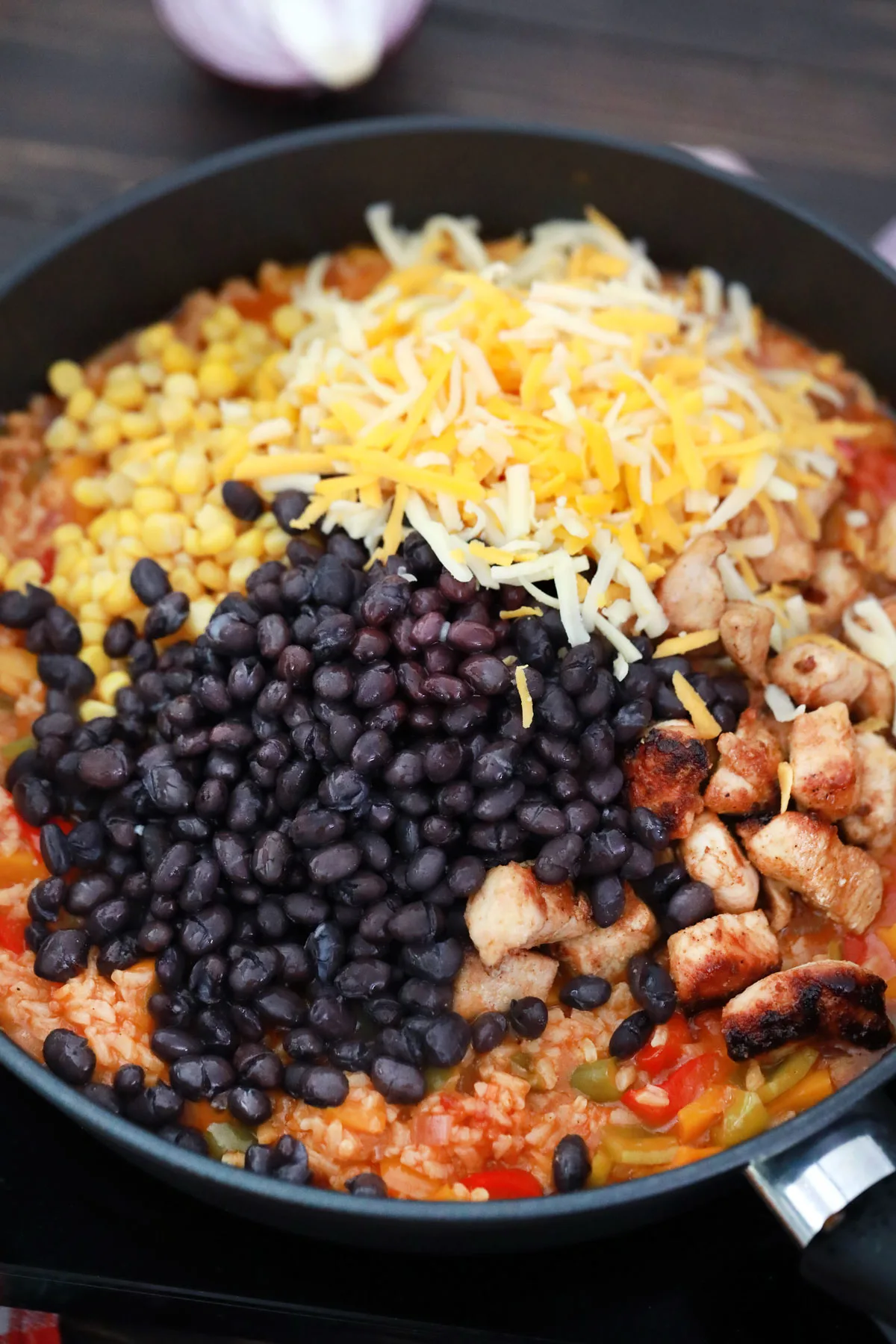 Adding beans, cheese and chicken to skillet mixture.