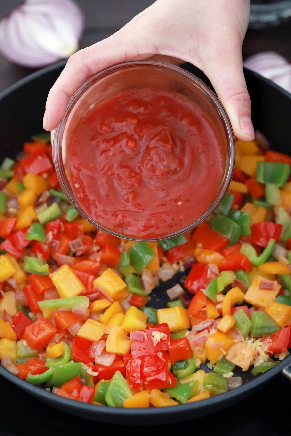Adding salsa to skillet with cooked veggies.