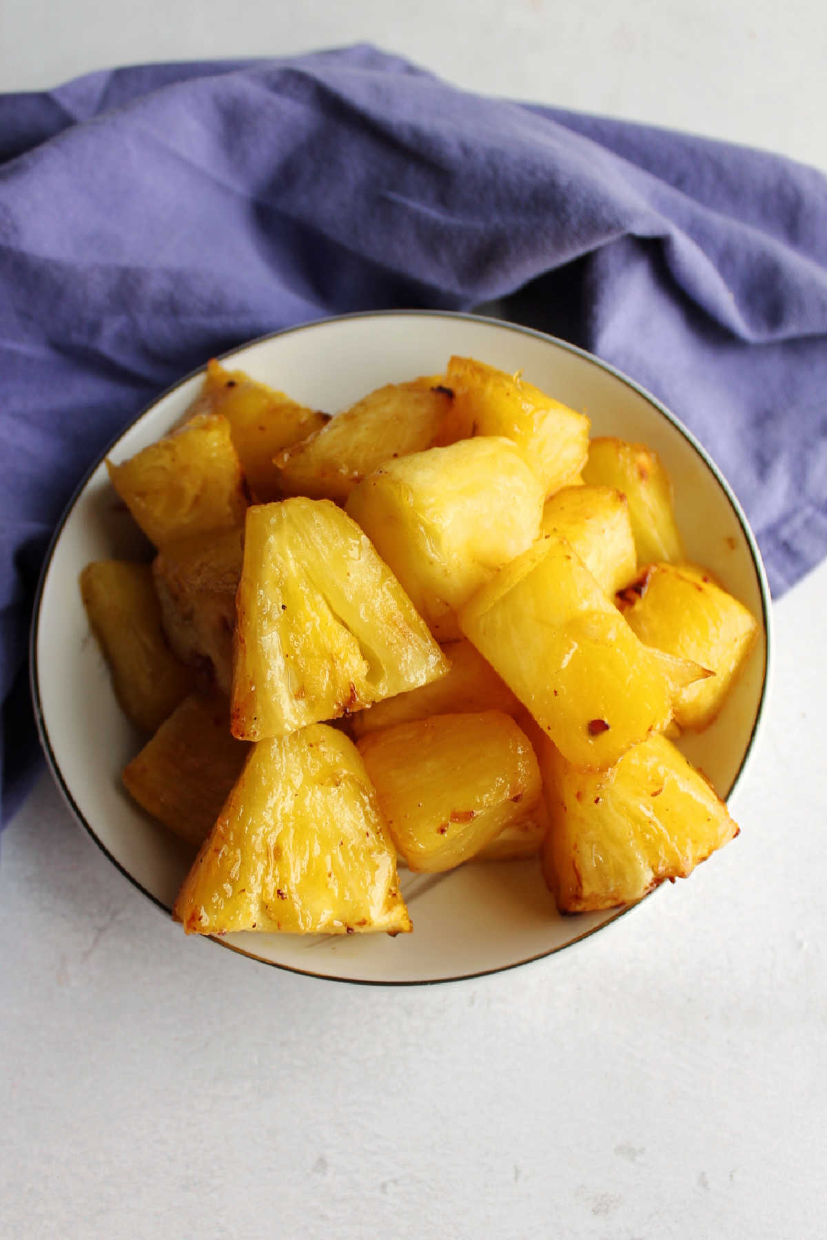 Bowl of glossy butter and brown sugar coated pineapple that has been cooked in an air fryer.