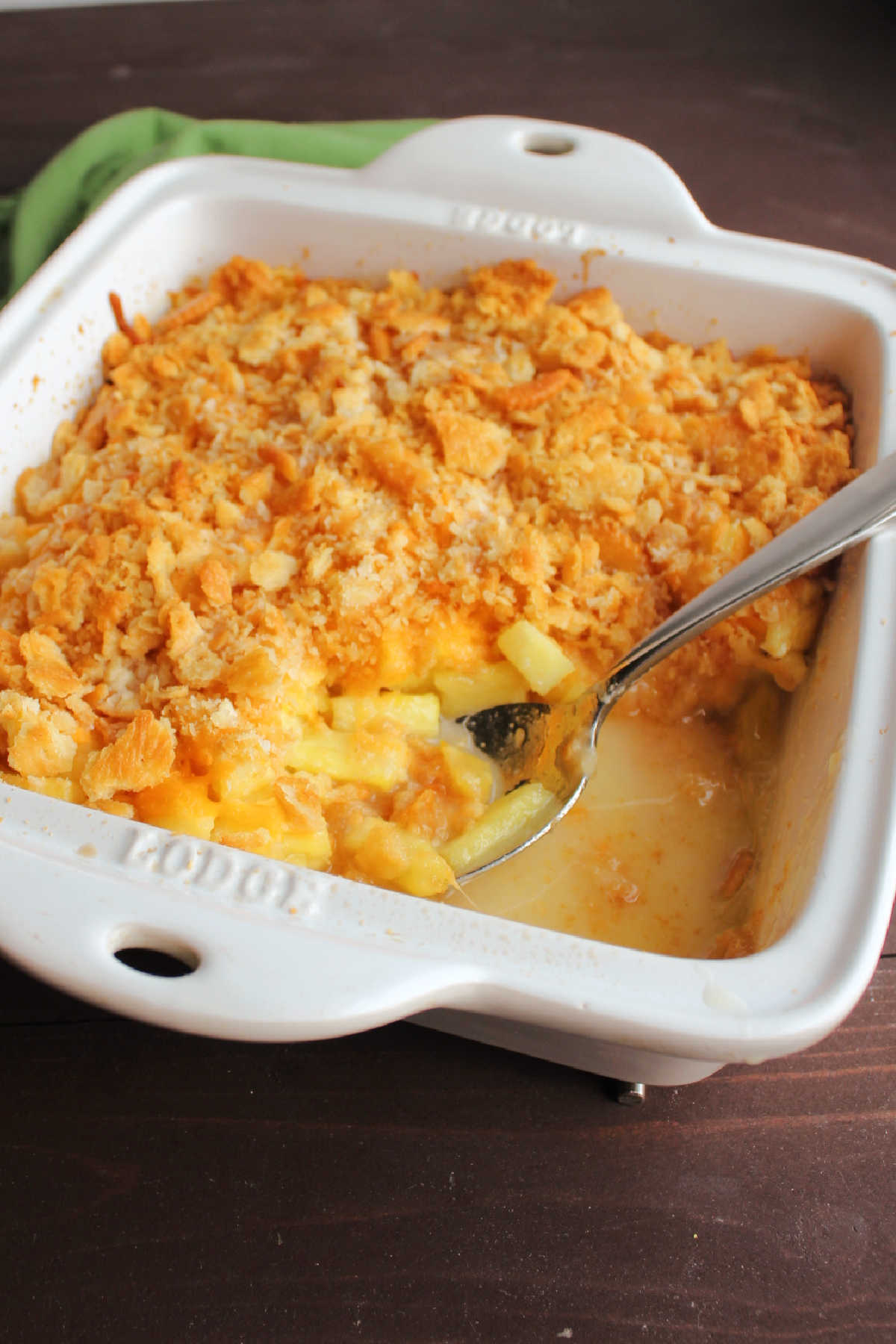 Baked southern pineapple casserole with a serving spoon in the corner. 