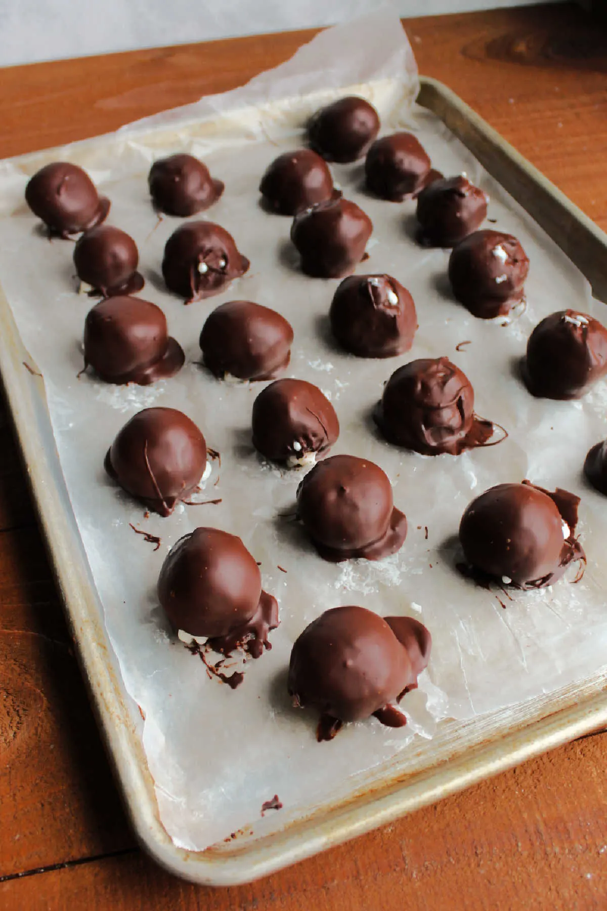 Chocolate dipped coconut truffles on wax paper setting up.