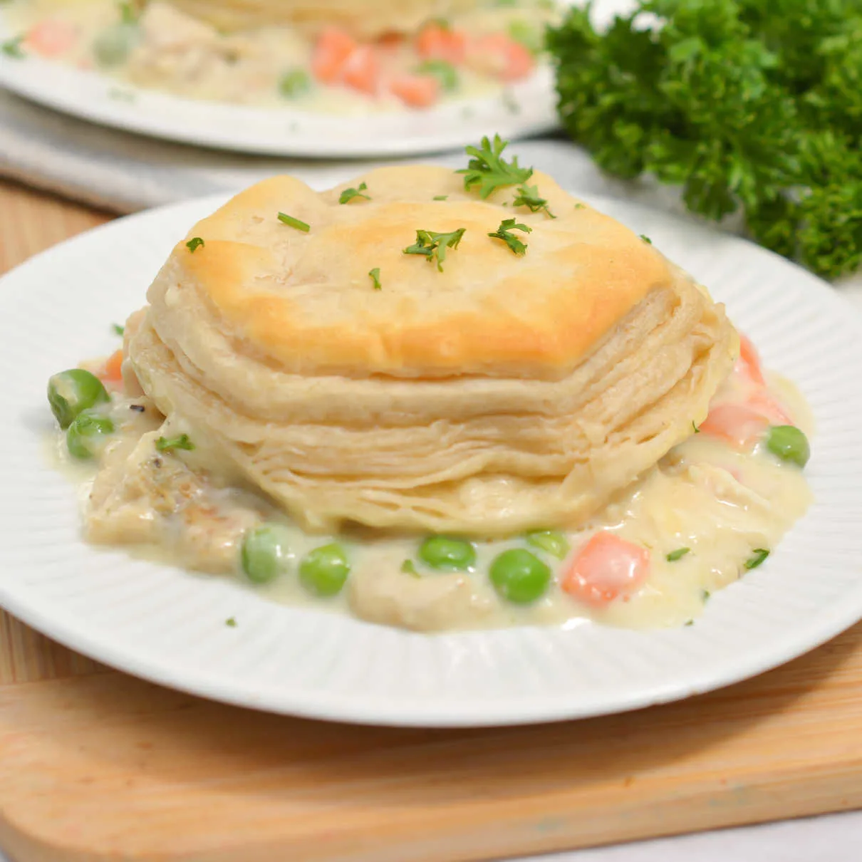 Dinner plate with chicken and veggies in creamy gravy topped with flaky golden biscuit.