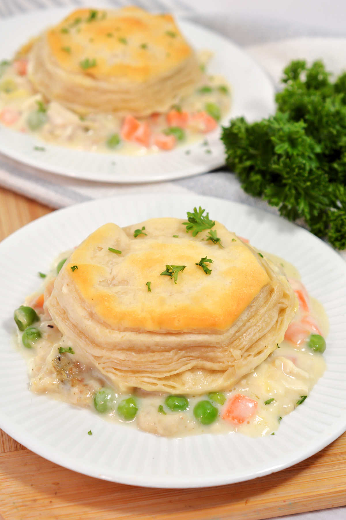 Two servings of chicken and biscuit casserole topped with fresh parsley, ready to eat.