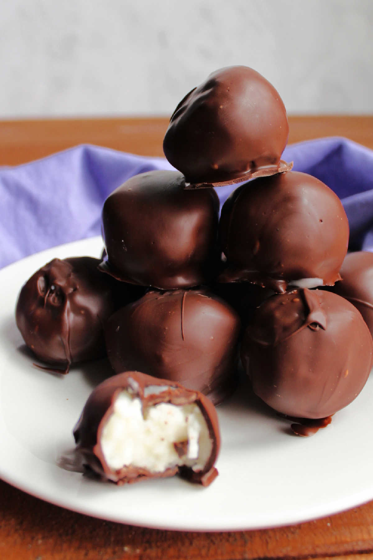 Stack of chocolate coated truffles with one in the front showing white center. 