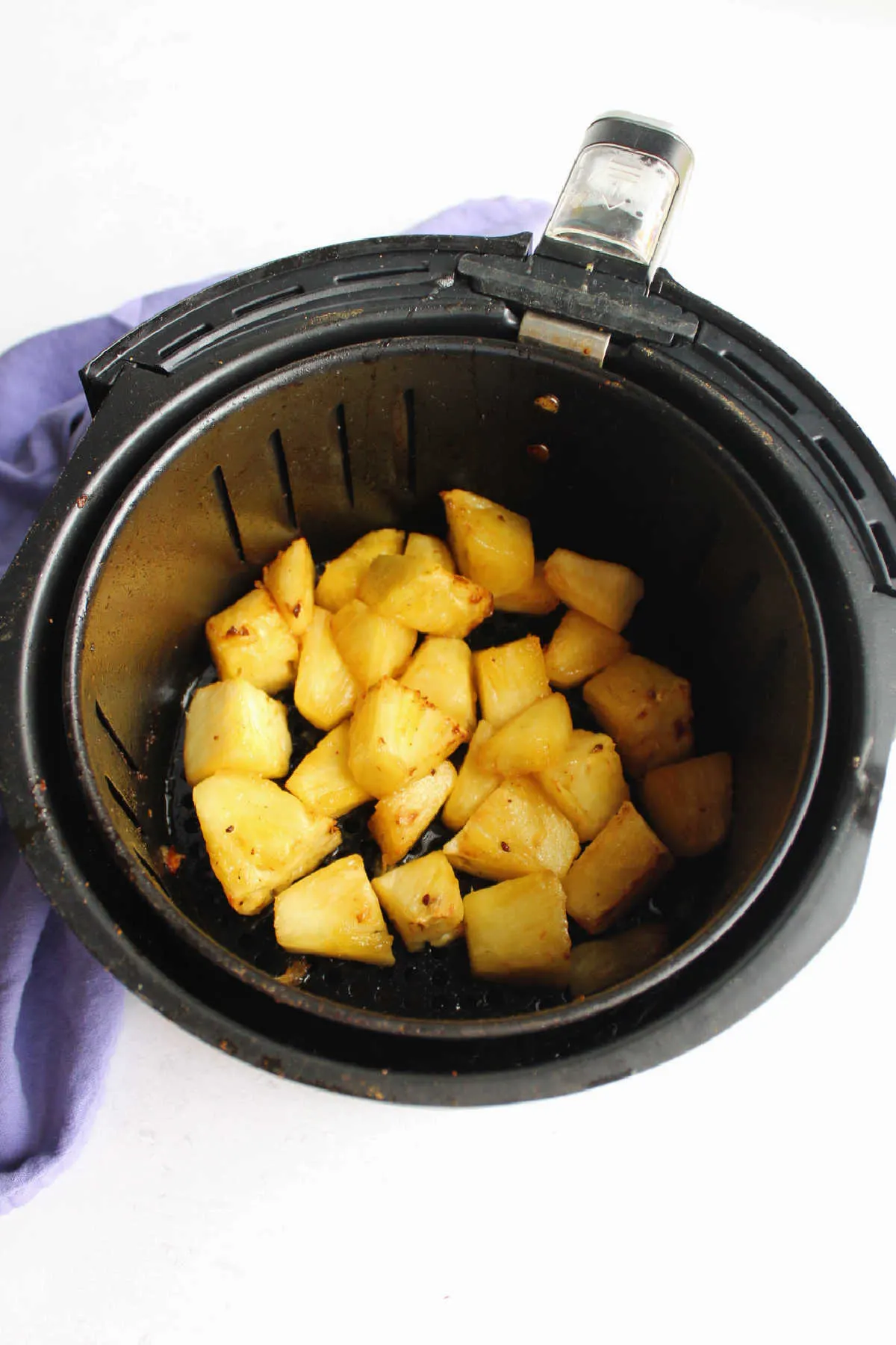 Pineapple chunks in air fryer basket, ready to go.
