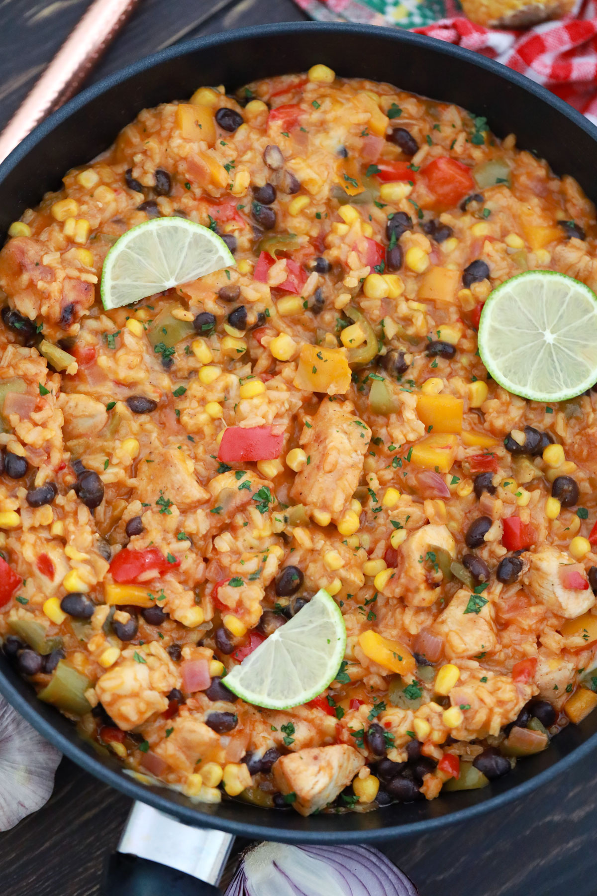 Skillet filled with one pot meal including chicken, rice, beans, peppers, cheese and more for a fun tex-mex meal.